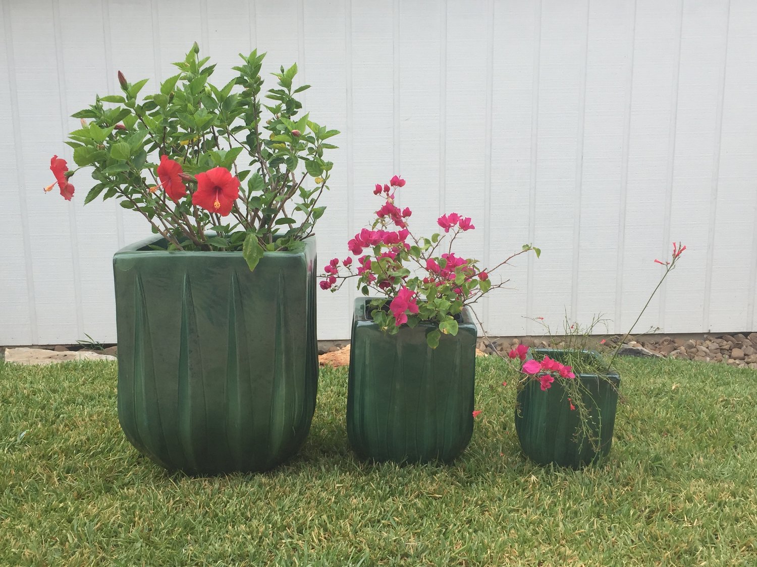 An image of three green square planters in a front yard setting.